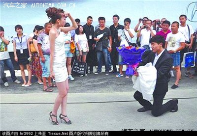长春汽博会,一位吉林帅哥手捧一大束玫瑰花对着台上的车模单膝跪地向